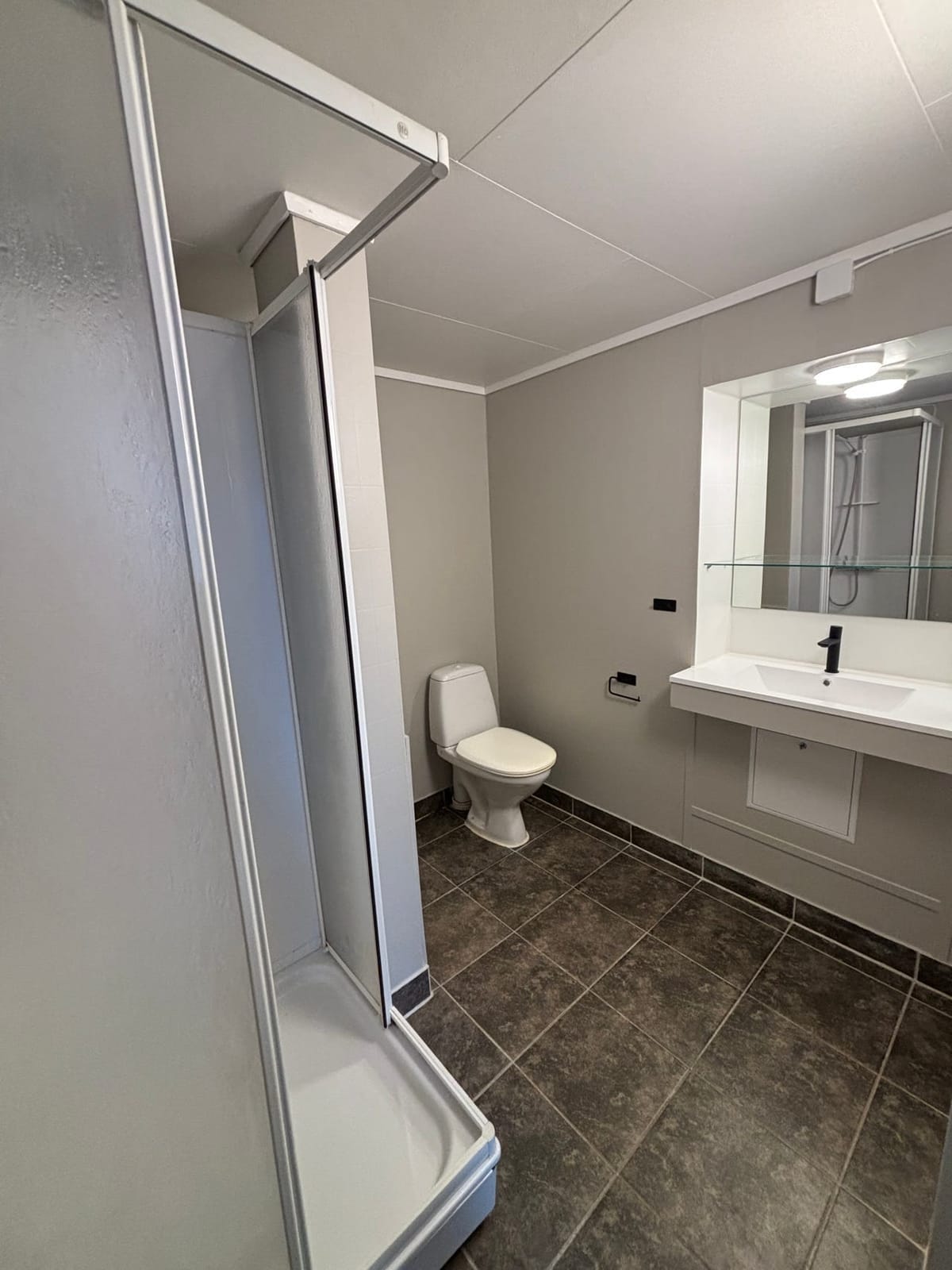Badet med dusjkabinett, servant og speil